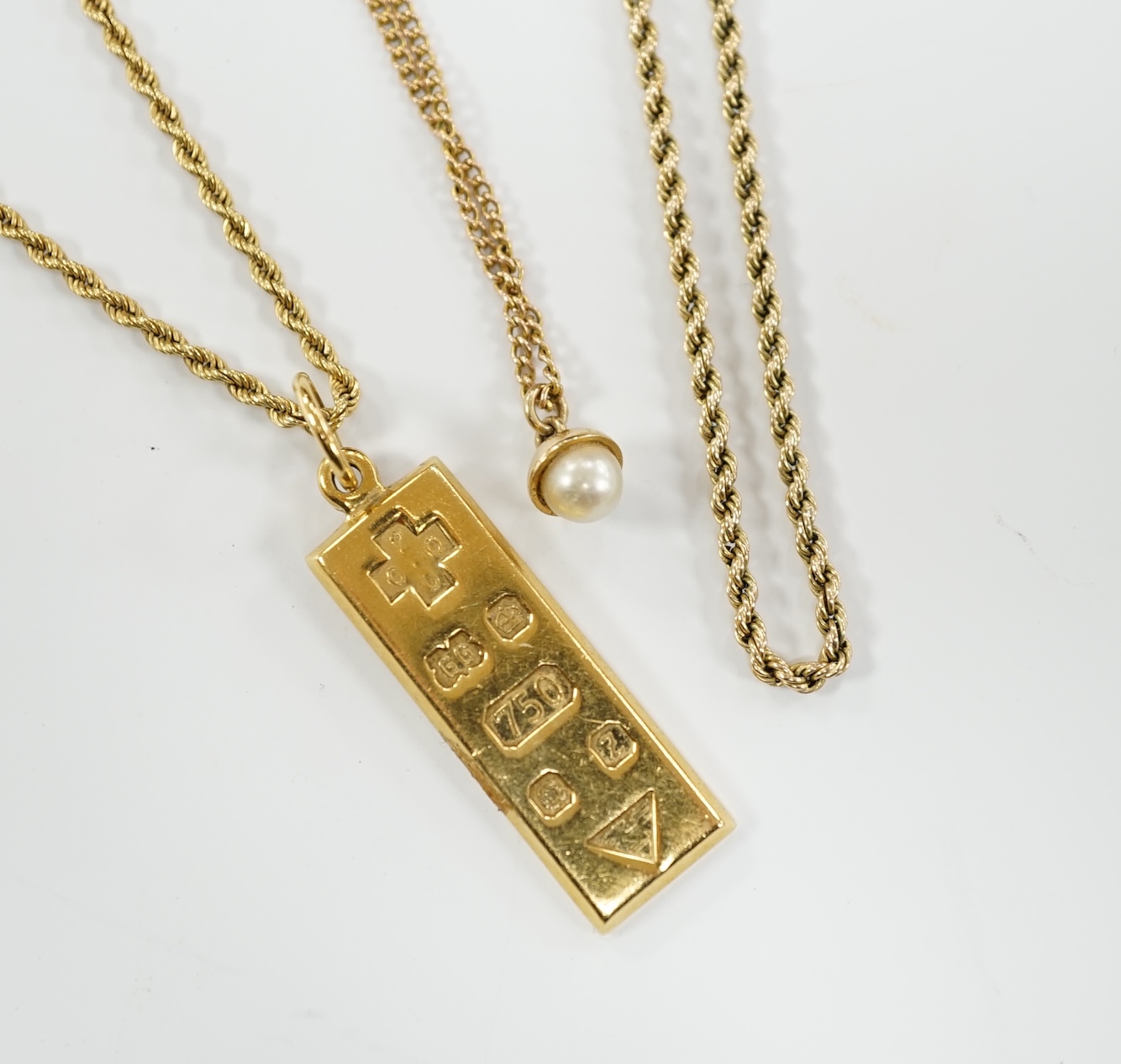 An 18ct gold ingot pendant on an 18k chain, 26.7 grams and two 9ct chains, one with cultured pearl pendant, gross weight 16.8 grams.